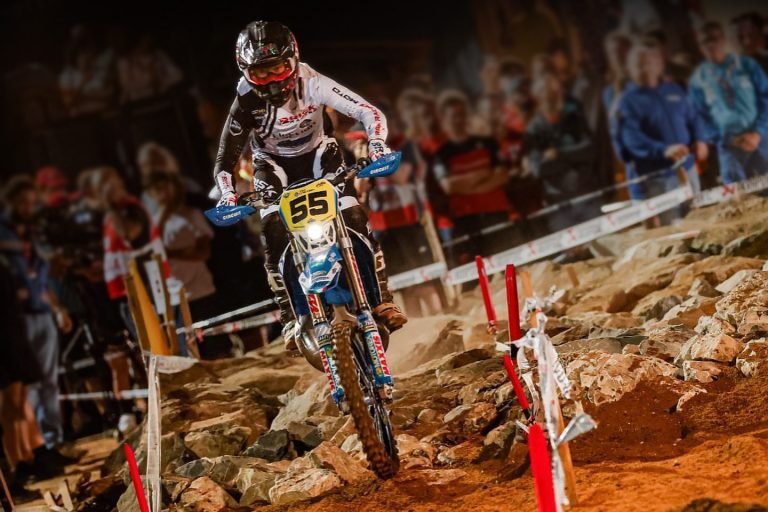 Enduro Racer moving through a rocky boulder section of the track coming straight at camera. He's wearing Risk Racing riding gear and his bike is equipped with Plews Tyres